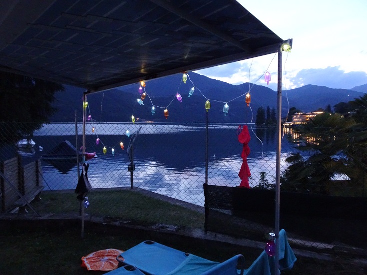 Campsite at lake orta at dusk with fairy lights around the awning.